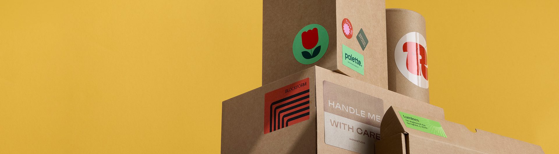 Stacked cardboard boxes with colorful stickers, including a red tulip.