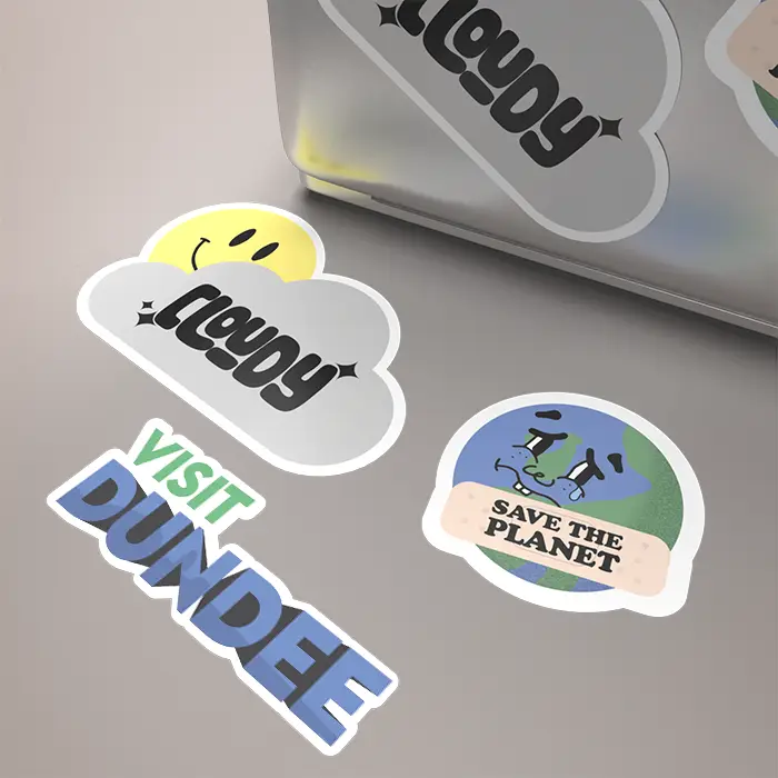 A laptop adorned with various colorful stickers including a smiley face and 'Visit Dundee'.